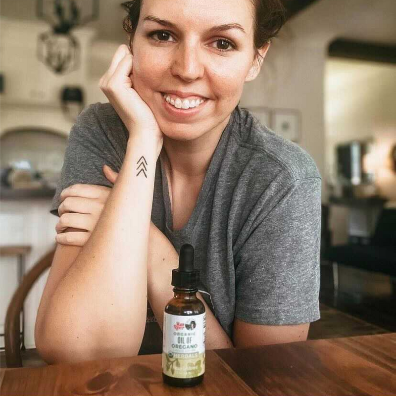 woman sitting behind oil of oregano herbals liquid drops