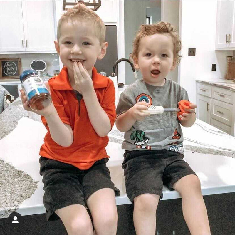 boys sitting on counter holding gummies
